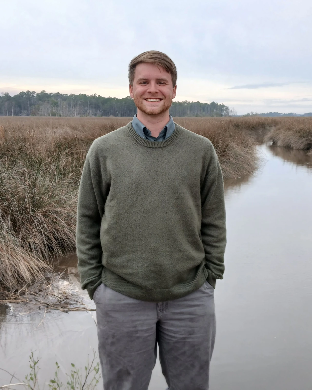 Reade Ward in a green sweater beside a marsh channel.