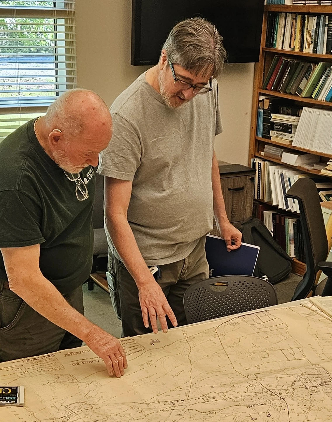 Two people leaning over a large paper map during a discussion; photograph supplied for Skip Van Bloem.